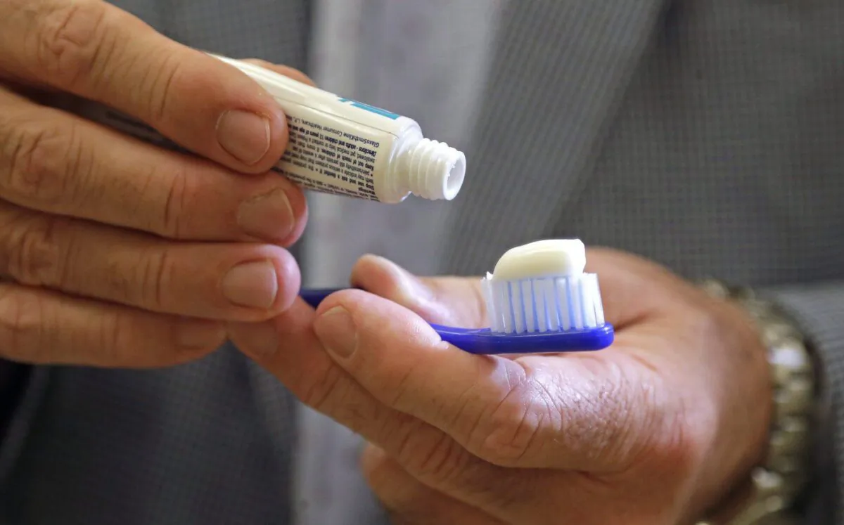 A toothbrush and toothpaste is held in Seattle on Aug.3, 2018. (The Canadian Press/Elaine Thompson)