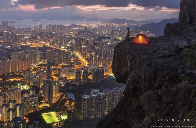 2015 年国家地理国际摄影大赛（青年组）冠军，香港摄影师 Kelvin Yueng 拍摄的《追逐梦想的野孩子的世界》，他在帐篷旁俯瞰香港夜景。（图片由图片提供杨开文)