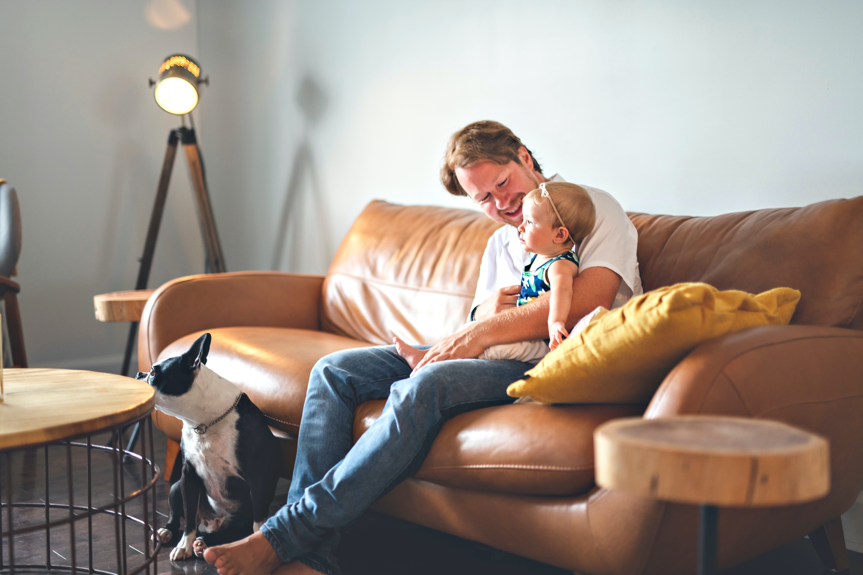 man and baby on couch with dog in the room