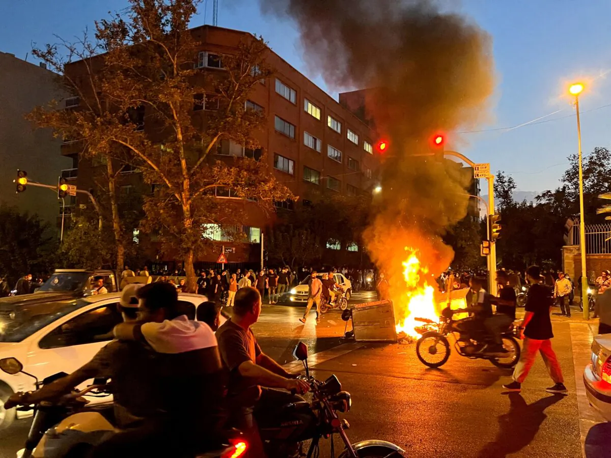 A police motorcycle burns during a protest over the death of Mahsa Amini, a woman who died after being arrested by the Islamic republic's "morality police," in Tehran, Iran, on Sept. 19, 2022. (WANA (West Asia News Agency) via Reuters)