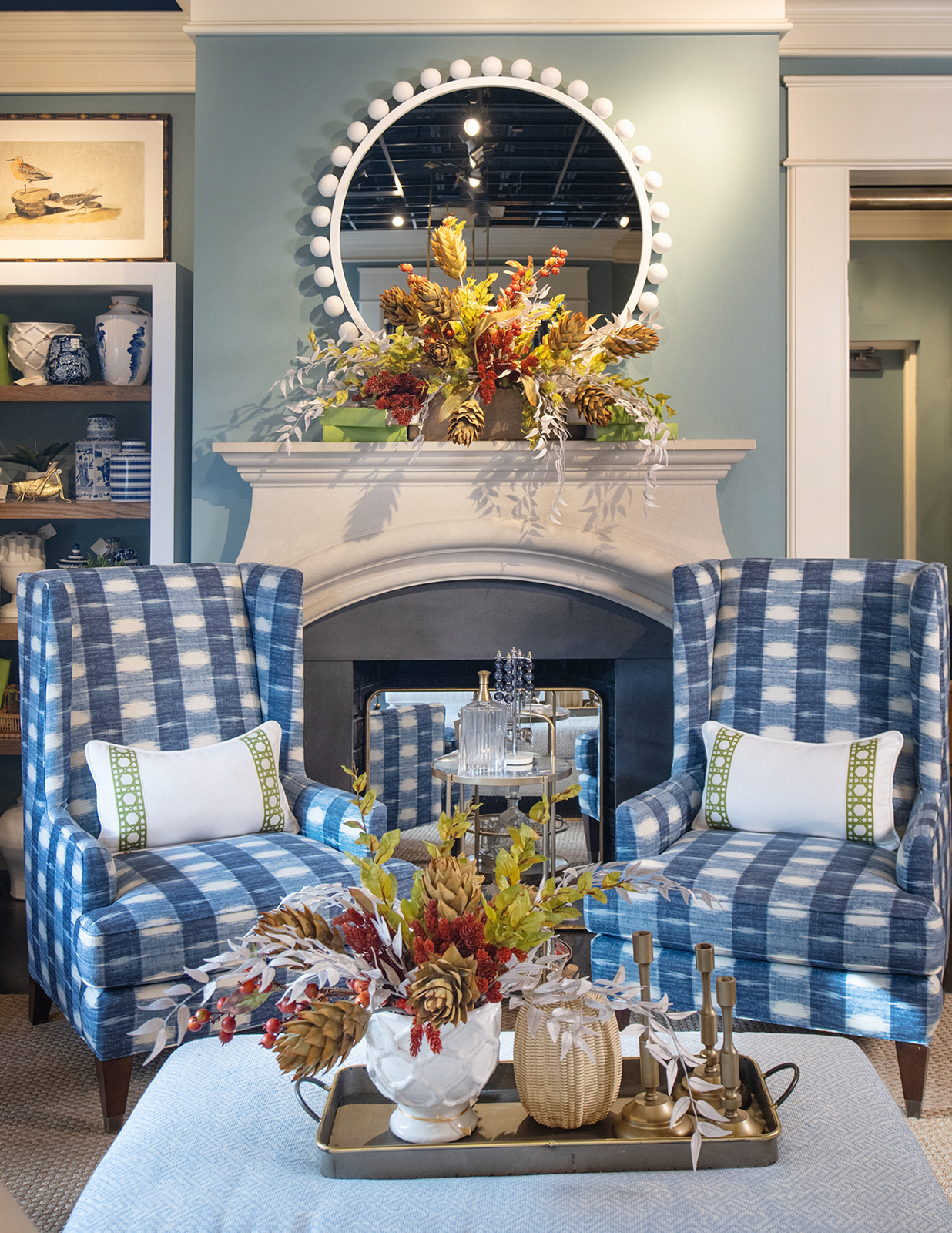 Matching fall foliage centerpieces adorn a fireplace mantel and ottoman.