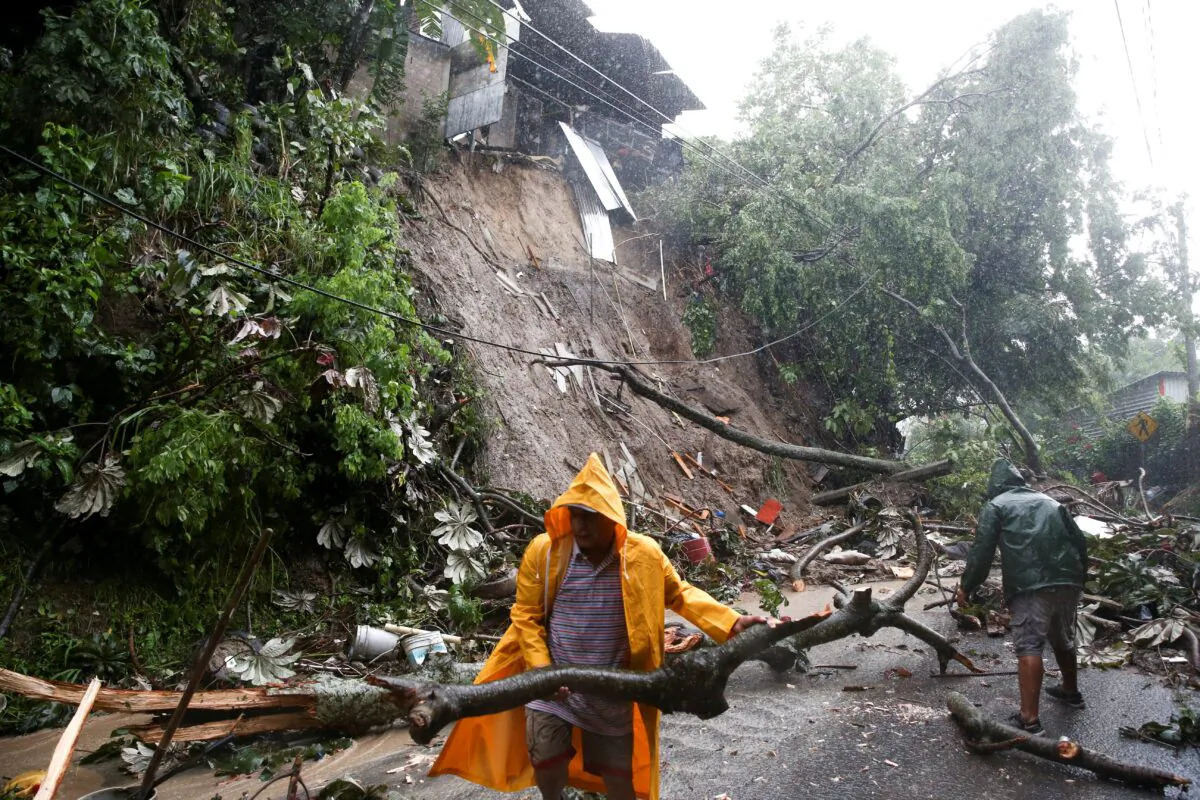 Residents clean a mudslide in a road while Tropical Storm Julia hits with wind and rain, in San Salvador, El Salvador, on Oct. 10, 2022. (Jose Cabezas/Reuters)