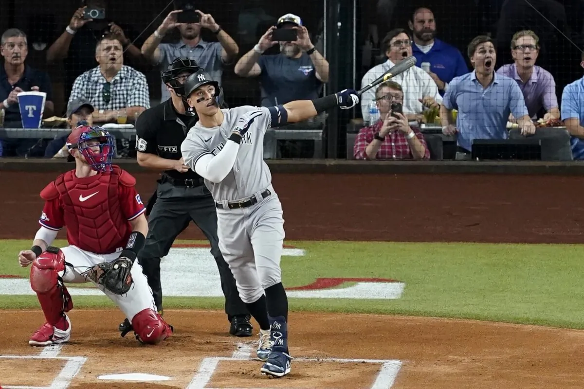 New York Yankees' Aaron Judge hits a solo home run, his 62nd of the season, as Texas Rangers catcher Sam Huff, left, and umpire Randy Rosenberg, rear, look on in the first inning of the second baseball game of a doubleheader in Arlington, Texas, on Oct. 4, 2022. (Tony Gutierrez/AP Photo)
