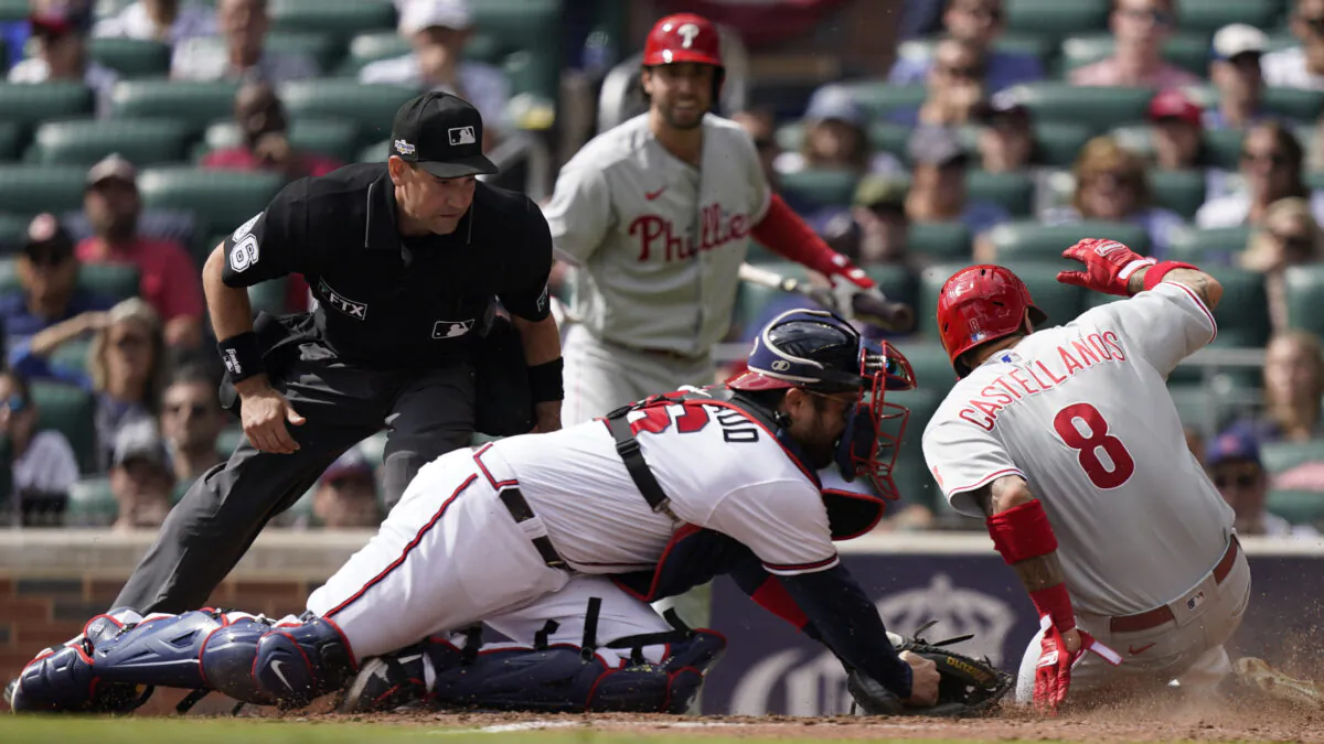 Philadelphia Phillies right fielder Nick Castellanos (8) scores against Atlanta Braves catcher Travis d'Arnaud (16) during the third inning in Game 1 of a National League Division Series baseball game in Atlanta on Oct. 11, 2022. (Brynn Anderson/AP Photo)