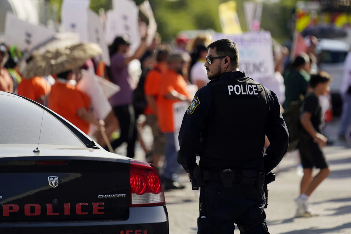 A Uvalde police officer watches as family and friends of those killed and injured in the school shootings at Robb Elementary take part in a protest march and rally in Uvalde, Texas, on July 10, 2022. (Eric Gay/AP Photo)
