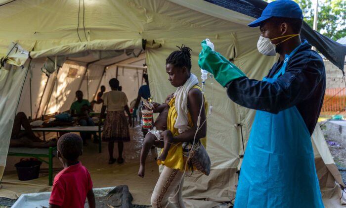 2022 年 10 月 7 日，在海地太子港人口稠密的社区太阳城，一名妇女带着她出现霍乱症状的孩子在无国界医生组织的诊所接受治疗。（Richard Pierrin/AFP via Getty图片）