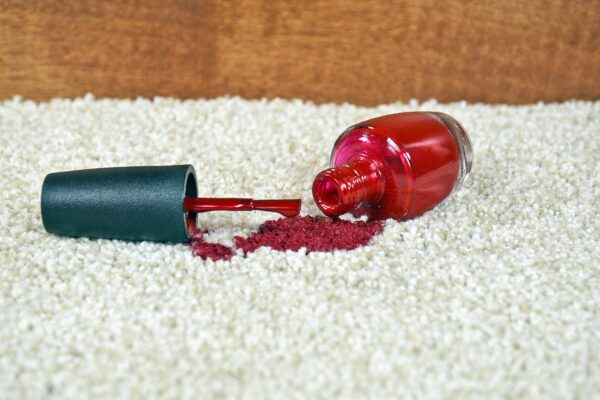 Red nail polish spills on light colored carpet