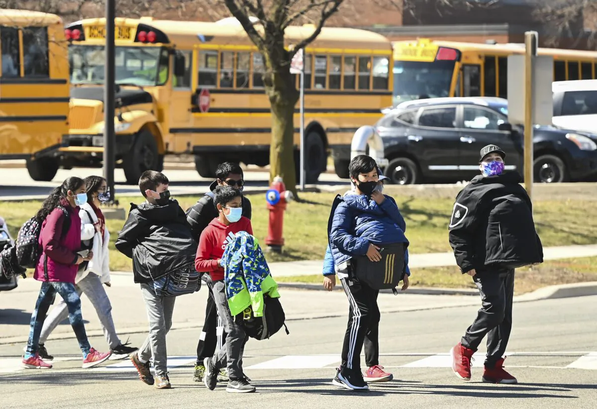 Students cross the street at Tomken Road Middle School in Mississauga, Ont., on April 1, 2021. (The Canadian Press/Nathan Denette)