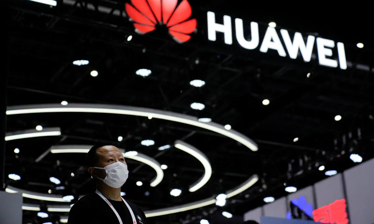 A person stands by a sign of Huawei during World Artificial Intelligence Conference in Shanghai on Sept. 1, 2022. (Aly Song/Reuters)