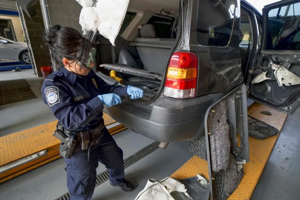 A U.S. Customs and Border Protection agent searches an automobile for contraband in the line to enter the United States at the San Ysidro Port of Entry in California on Oct. 2, 2019. (Sandy Huffaker/AFP via Getty Images)
