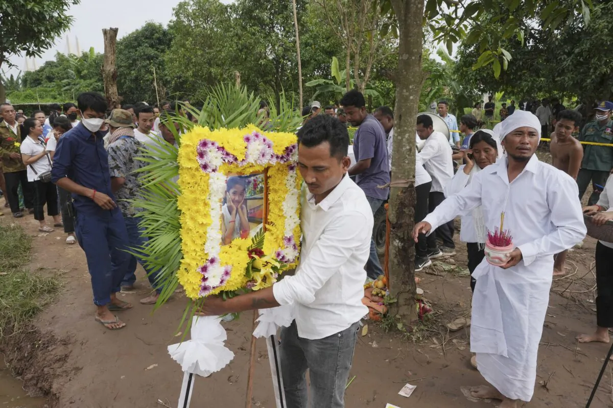 A portrait photo of a teen victim, Chanda July, is carried by her relative during her funeral procession in Koh Chamroeun village, east of Phnom Penh, Cambodia, on Oct. 14, 2022. (Heng Sinith/AP Photo)