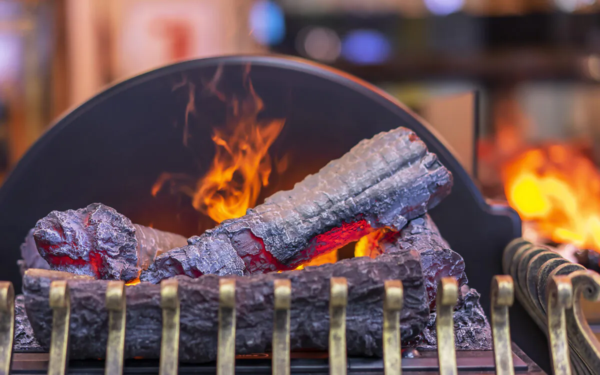 You can use imitation logs and brass furnishings to enhance the look of an electric fireplace "flame." (Dreamstime/TNS)