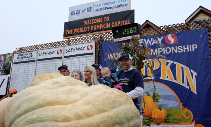 2022 年 10 月 10 日，在加利福尼亚州半月湾举行的西夫韦世界锦标赛南瓜称重比赛中，特拉维斯·金格（远 R）和他的家人在他们 2,560 磅重的南瓜 Maverick 旁边。（David Lam/NTD）