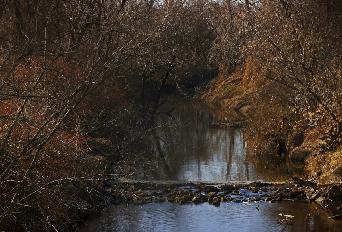 Water flows in Coldwater Creek behind a row of homes at Belcroft Drive and Old Halls Ferry Road in Missouri's St. Louis County on Dec. 9, 2021. (Christian Gooden/St. Louis Post-Dispatch via AP)