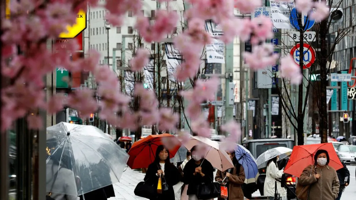 Pedestrians seen behind artificial cherry blossom decorations at a shopping district on the first day after the lifting of COVID-19 restrictions imposed on Tokyo and 17 other prefectures, in Tokyo, Japan, on Mar. 22, 2022. (Kim Kyung-Hoon/Reuters)