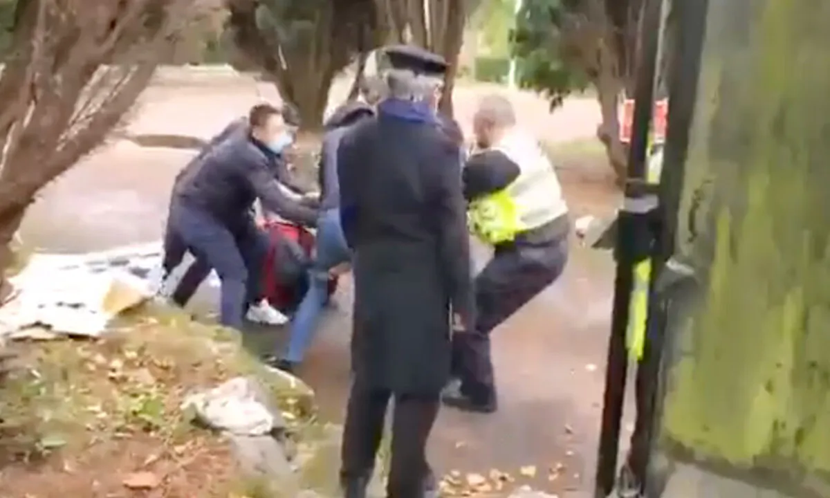 Screenshot from video showing a police officer trying to rescue a Hong Kong protester who was being beaten at the Chinese consulate in Manchester, England, on Oct. 16, 2022. (Screenshot via The Epoch Times)