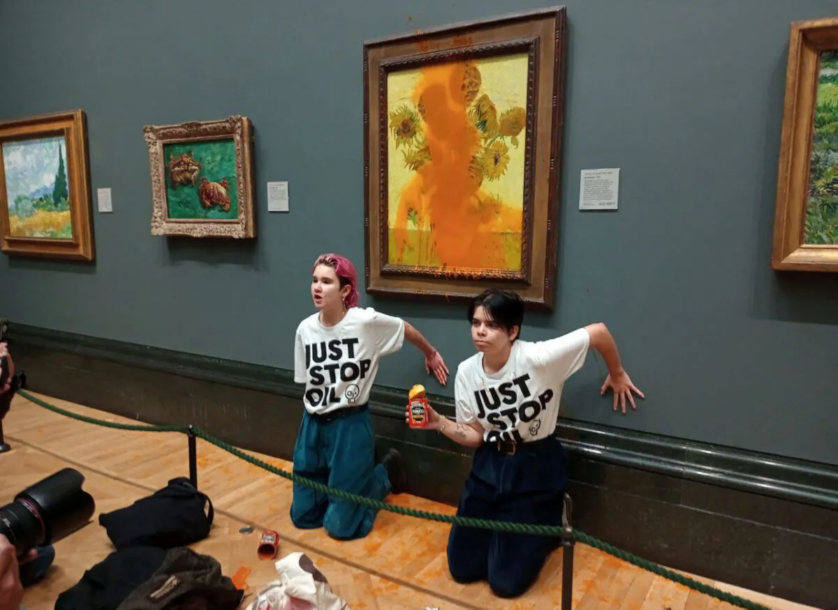 Activists with Just Stop Oil glue their hands to the wall after throwing soup at  Vincent van Gogh's "Sunflowers" at the National Gallery in London, UK, on Oct. 14, 2022. (Just Stop Oil/Handout via Reuters)