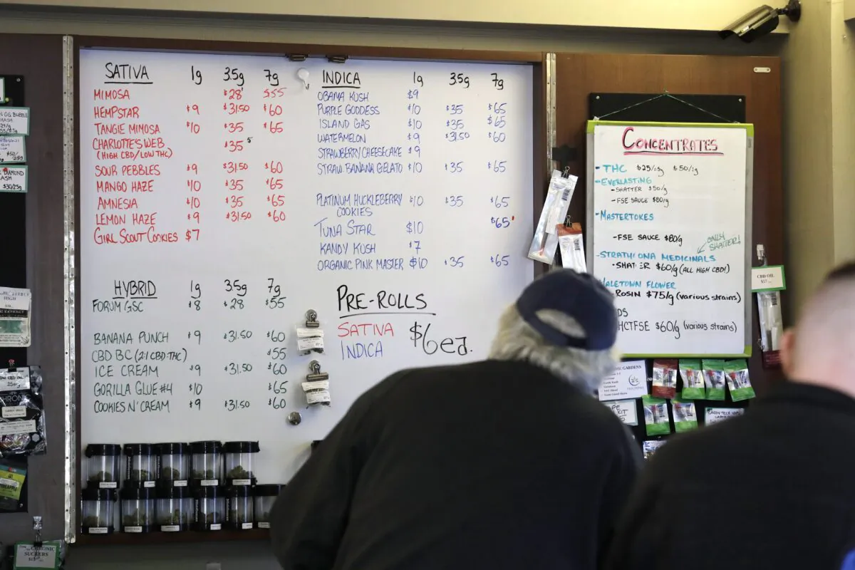 Customers stand at a counter where prices of marijuana products are posted at the Medicinal Cannabis Dispensary, an unlicensed marijuana shop, in Vancouver on Oct. 9, 2019. (Elaine Thompson/AP Photo)
