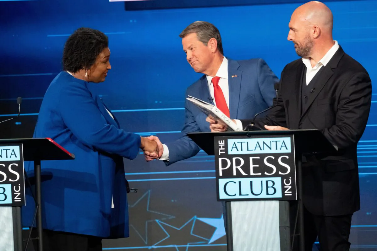 Stacey Abrams (L), the Democratic nominee for Georgia governor, shakes hands with incumbent Republican Brian Kemp (C), as Libertarian candidate Shane Hazel looks on, at the Atlanta Press Club debate on Oct. 17, 2022. (Ben Gray/AP Photo)