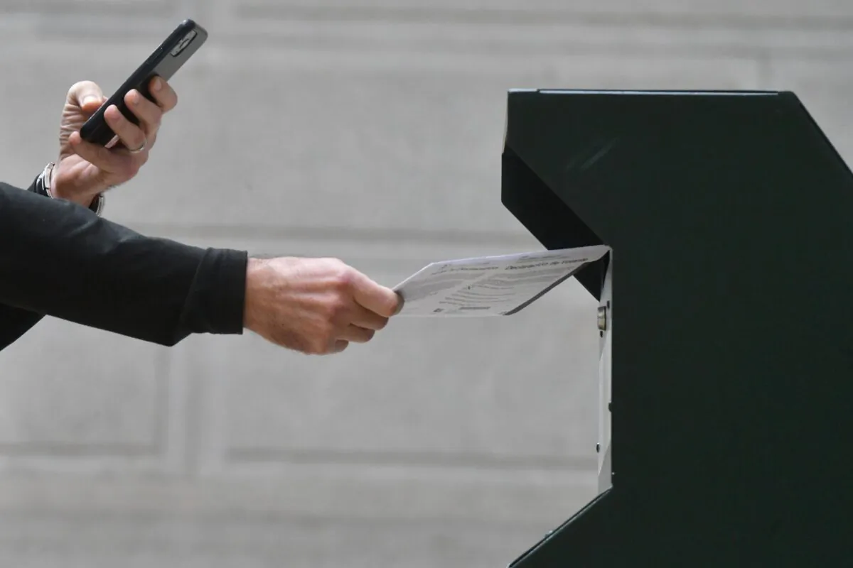 A man photographs himself depositing his ballot in an official ballot drop box while a long line of voters queue outside of Philadelphia City Hall at the satellite polling station in Philadelphia, Pa., on Oct. 27, 2020. (Mark Makela/Getty Images)
