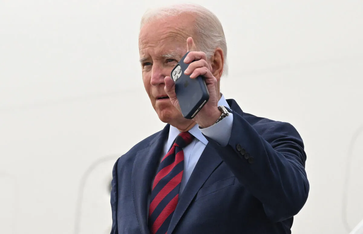 U.S. President Joe Biden waves with his phone in his hand as he disembarks from Air Force One upon arrival at Los Angeles International Airport in Los Angeles, California, Oct. 12, 2022. (Saul Loeb/AFP via Getty Images)
