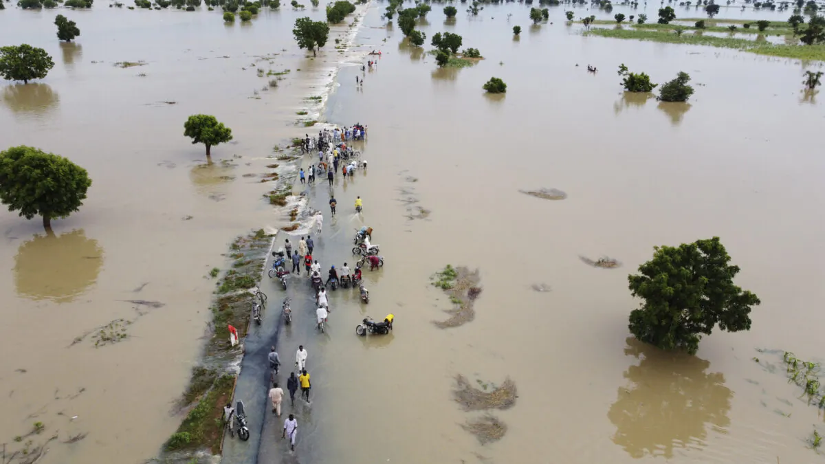 People walk through floodwaters after heavy rainfall in Hadeja, Nigeria, on Sept. 19, 2022. (AP Photo)