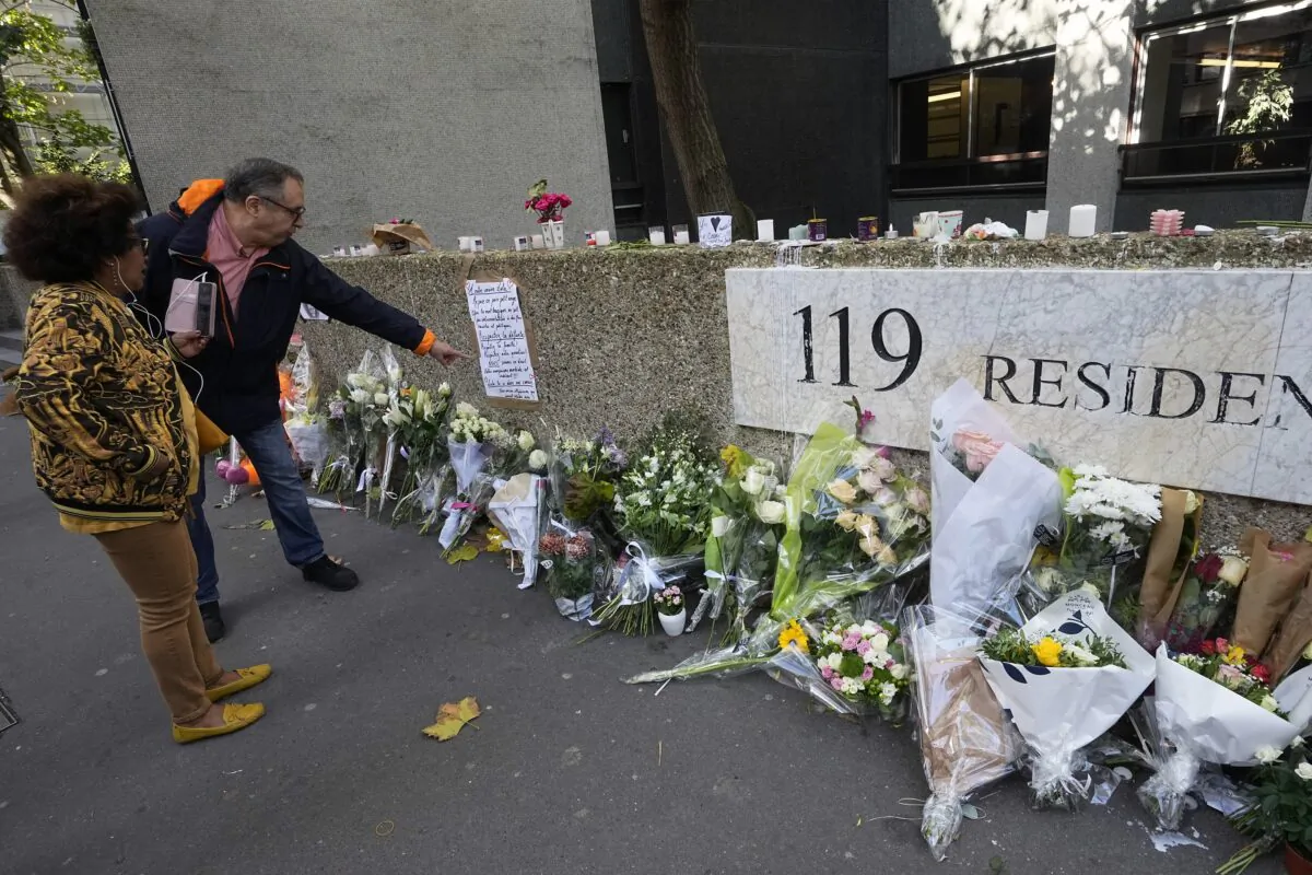 People stand outside the building where the body of 12-year-old schoolgirl was discovered in a trunk, in Paris on Oct. 19, 2022. (Michel Euler/AP Photo)