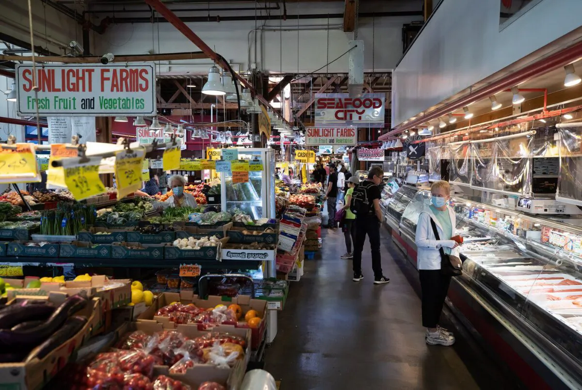 People shop for produce and seafood at the Granville Island Market in Vancouver, on July 20, 2022. (The Canadian Press/Darryl Dyck)