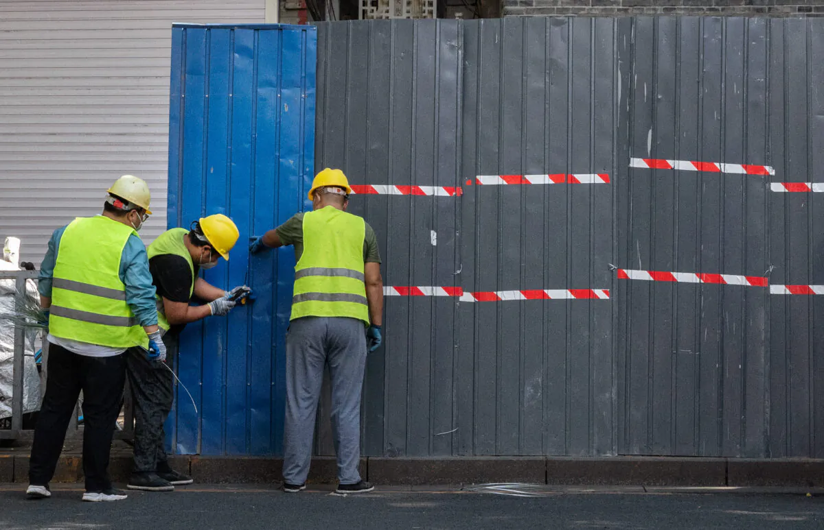 Workers erect a barrier fence around local residences and shops in lockdown, after new local cases of COVID-19 were found, on June 23, 2022 in the Sanlitun shopping district in Beijing, China. (Kevin Frayer/Getty Images)