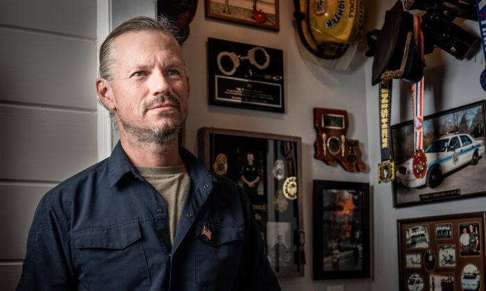 Michael Nichols stands in front memorabilia from his previous jobs in law enforcement, firefighting, and military at his home in King Ferry, N.Y., on Oct. 13, 2022. (Samira Bouaou/The Epoch Times)