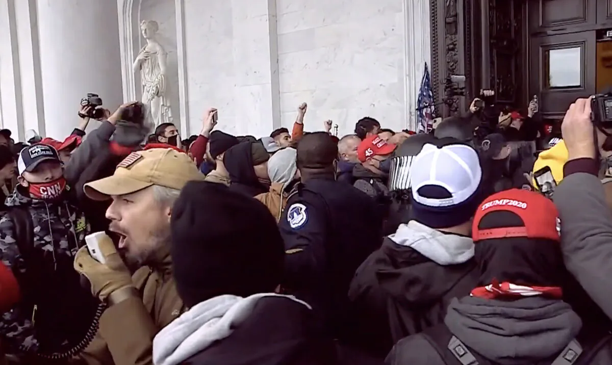 Retired police sergeant and Oath Keeper Michael Nichols uses a bullhorn to tell people to make way for the police officers they were extracting from the Capitol on Jan. 6, 2021. (U.S. Department of Justice/Screenshot via The Epoch Times)