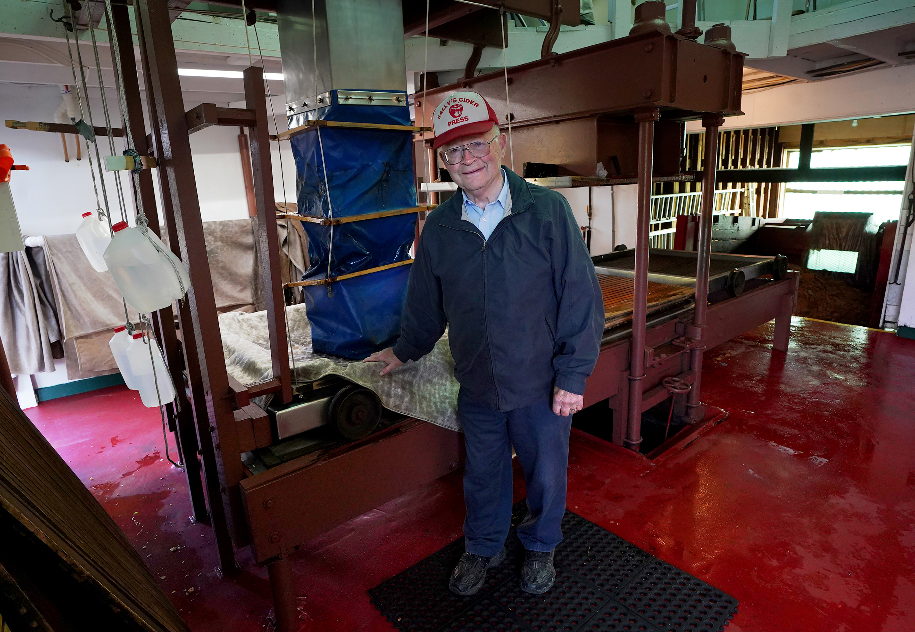 Tom Davis, 83, poses in front of his antique press at Sally's Cider Press, Oct. 6, 2022, in Harmony, Pennsylvania.