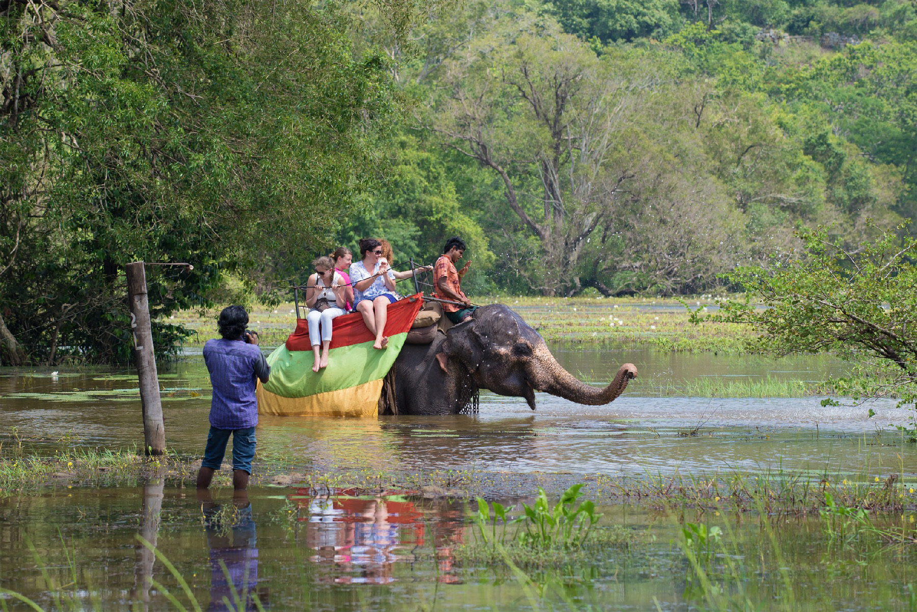 people riding an elephant wading through water