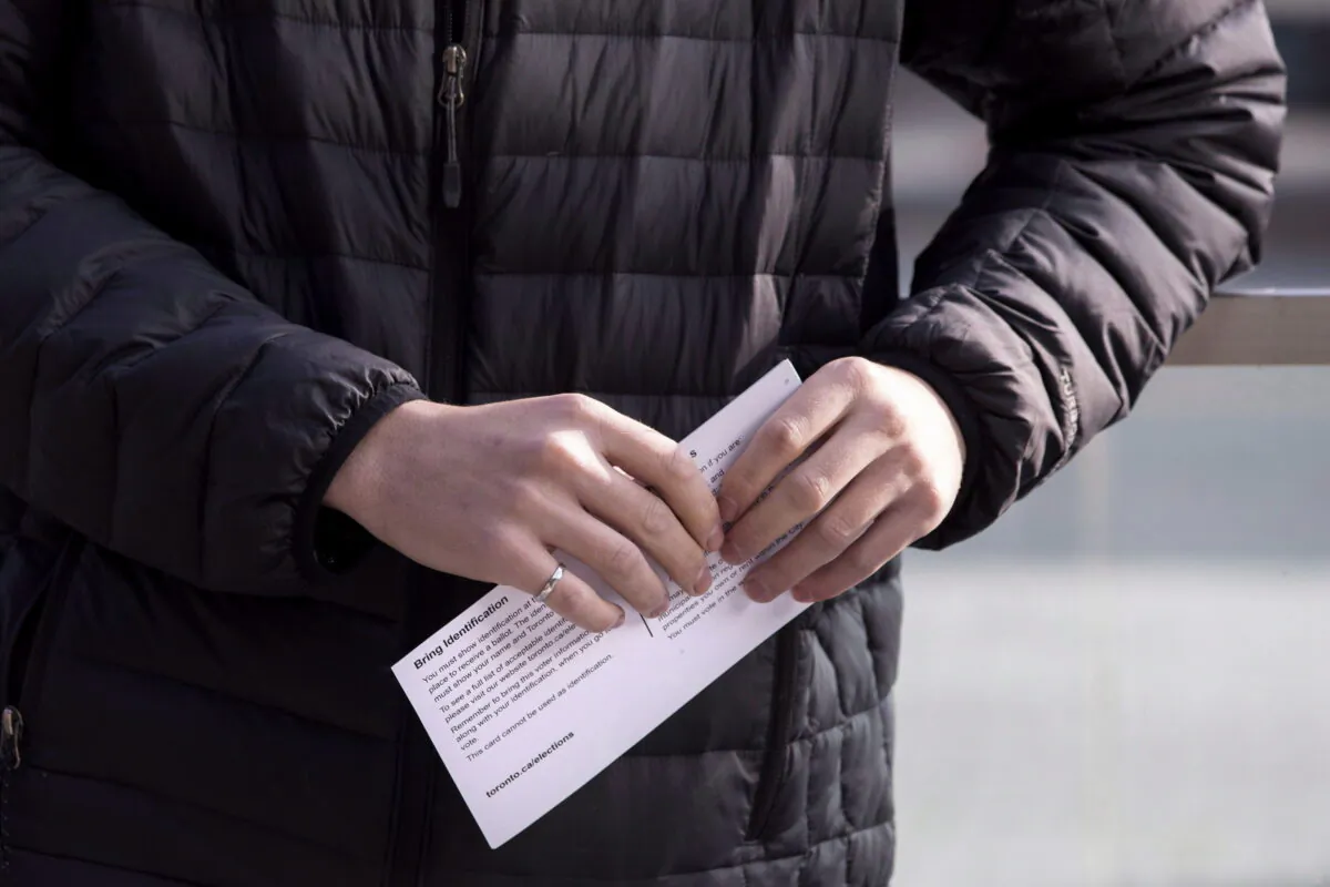 A man holds his voter registration card as he lines up outside a voting station to cast his ballot in the municipal elections in Toronto on Oct. 22 , 2018. (The Canadian Press/Chris Young)