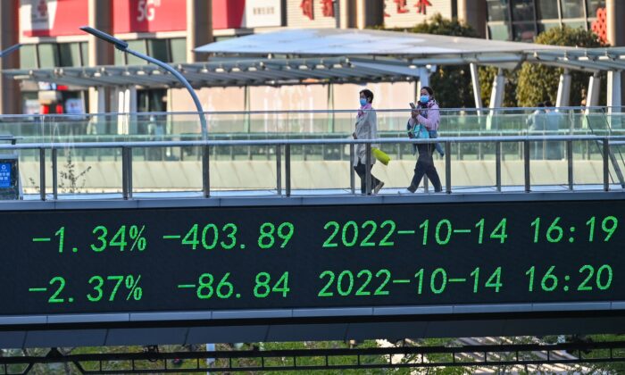 2022 年 10 月 17 日，在中国上海陆家嘴金融区，人们走过一座带有股票指示牌的桥。（Hector Retamal/法新社通过 Getty Images）