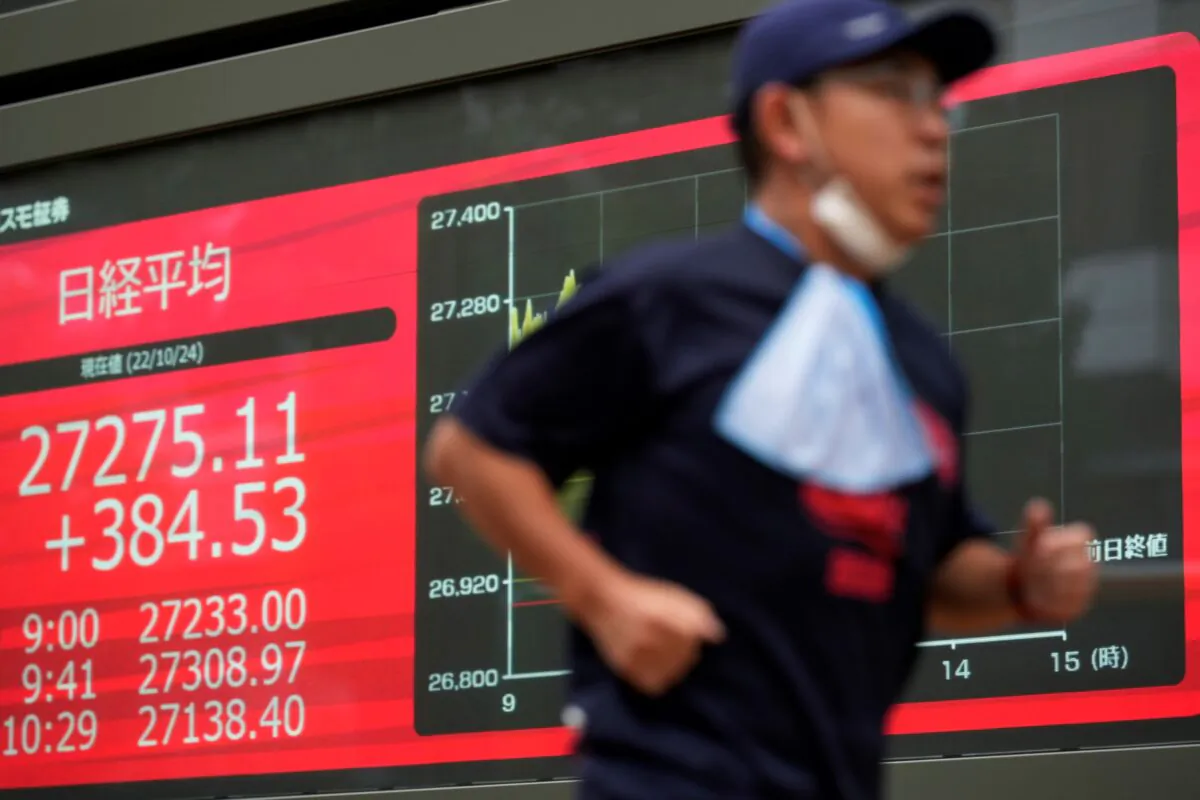 A man jogs past monitors showing Japan's Nikkei 225 index at a securities firm in Tokyo, Japan, on Oct. 24, 2022. (Hiro Komae/AP Photo)