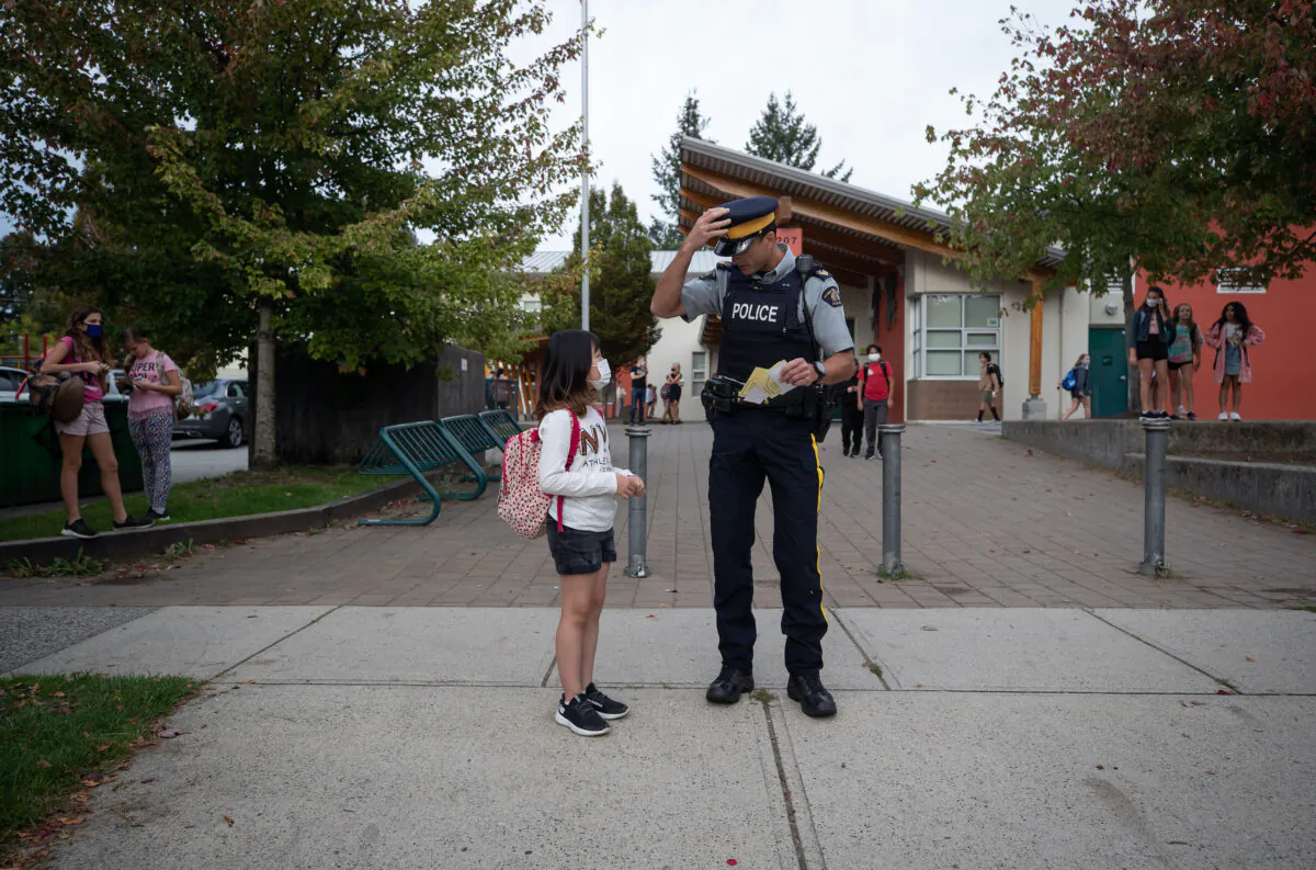An RCMP officer speaks with a student outside of an elementary school in North Vancouver on Sept. 9, 2021. (The Canadian Press/Darryl Dyck)
