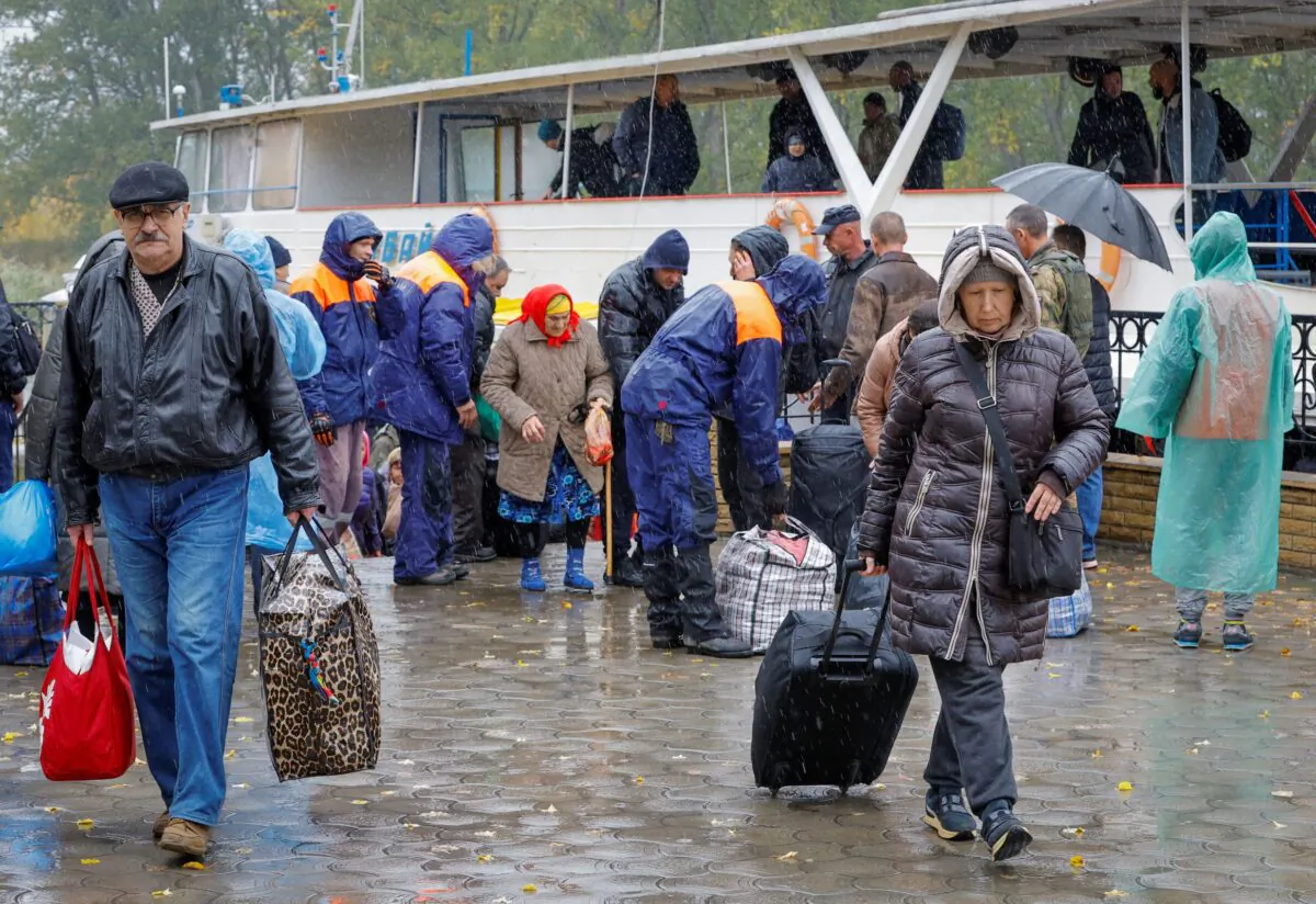 Civilians evacuated from the Russian-controlled city of Kherson walk from a ferry to board a bus heading to Crimea, in Russian-controlled Ukraine, on Oct. 23, 2022. (Alexander Ermochenko)