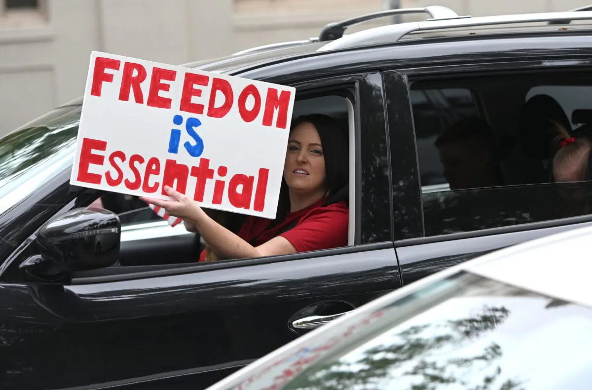 A driver holds out a sign as hundreds of people gather to protest the lockdown in spite of shelter-in-place rules still being in effect at California's state capitol building in Sacramento, Calif., on April 20, 2020. (Josh Edelson/AFP via Getty Images)