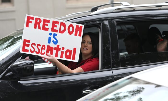 A driver holds out a sign as hundreds of people gather to protest the lockdown in spite of shelter-in-place rules still being in effect at California's state capitol building in Sacramento, Calif., on April 20, 2020. (Josh Edelson/AFP via Getty Images)