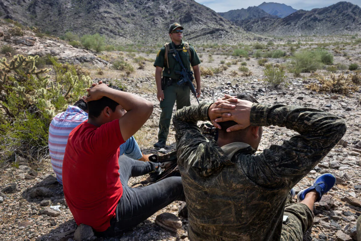 A U.S. Border Patrol agent with a group of illegal immigrants he tracked through rugged terrain at the Organ Pipe National Monument, Ariz., on Sept. 28, 2022. (John Moore/Getty Images)