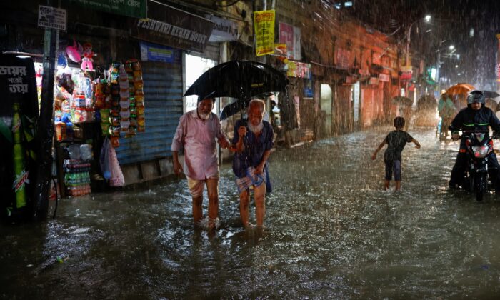 People wade through a flooded street amid continuous rain before the Cyclone Sitrang hits the country in Dhaka, Bangladesh, on Oct. 24, 2022. (Mohammad Ponir Hossain/Reuters)