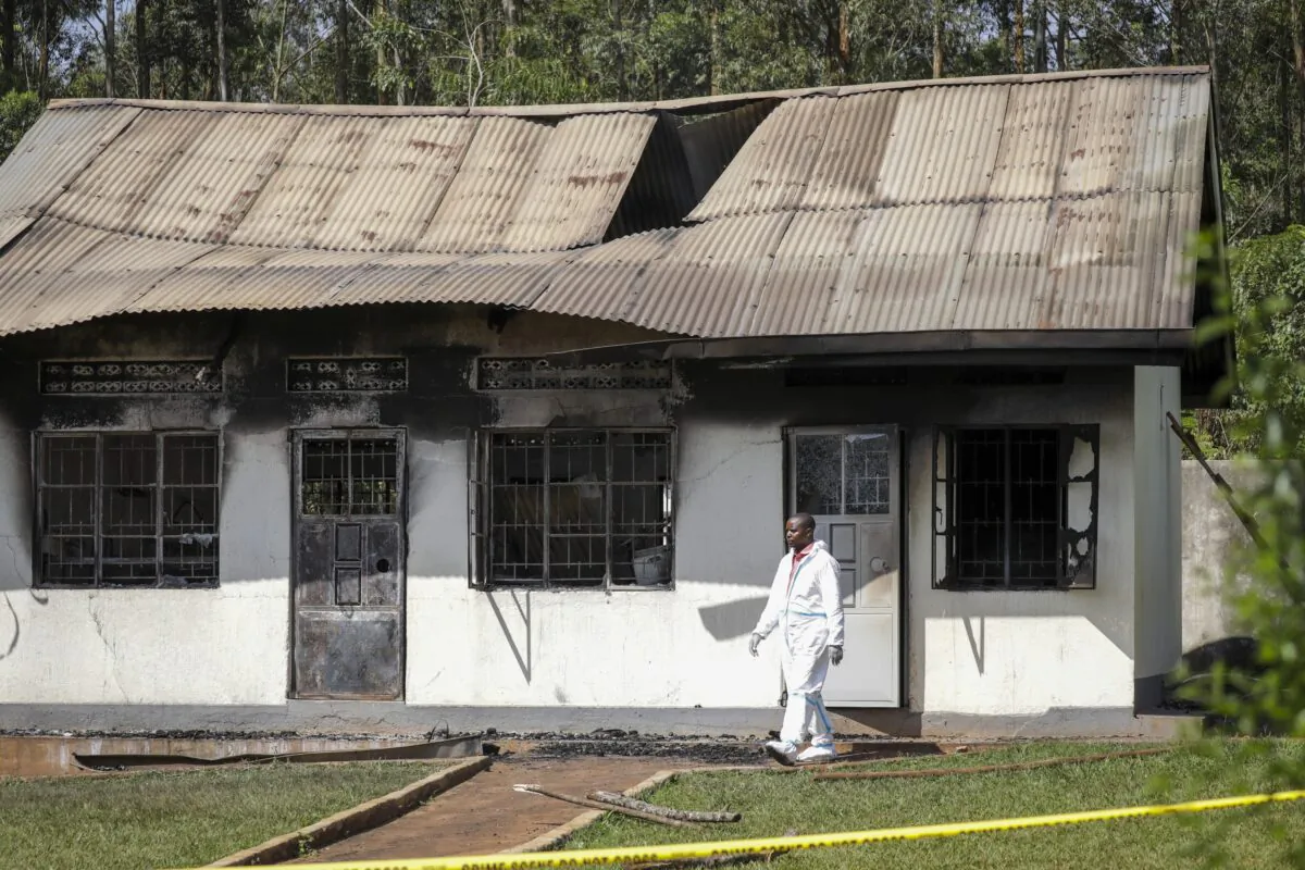 A forensics officer walks past a burned dormitory at the scene of a fire at the Salama School for the Blind in Luga village, Mukono district, Uganda, on Oct. 25, 2022. (Hajarah Nalwadda/AP Photo)