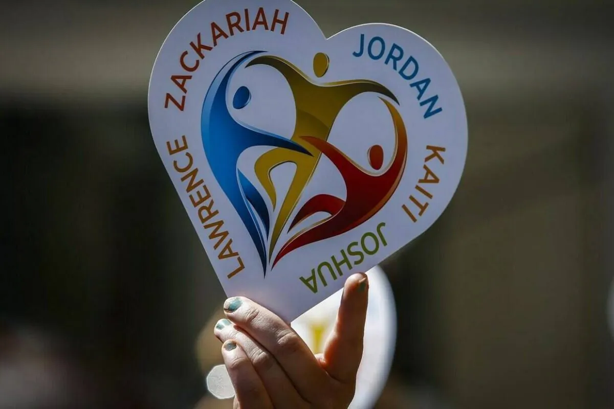 A family member of five slain students holds a heart sign with their names on it following a court decision in Calgary, Alta., May 25, 2016. (The Canadian Press/Jeff McIntosh)
