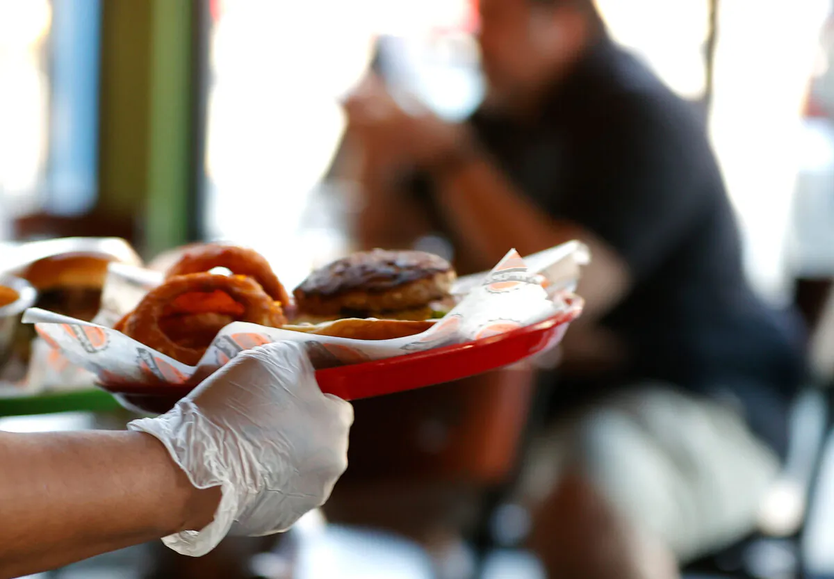 A server is delivering food wearing disposable gloves in Bad Daddy's Burger Bar as it reopened for dine-in seating in Decatur, Ga., on April 27, 2020. (Kevin C. Cox/Getty Images)