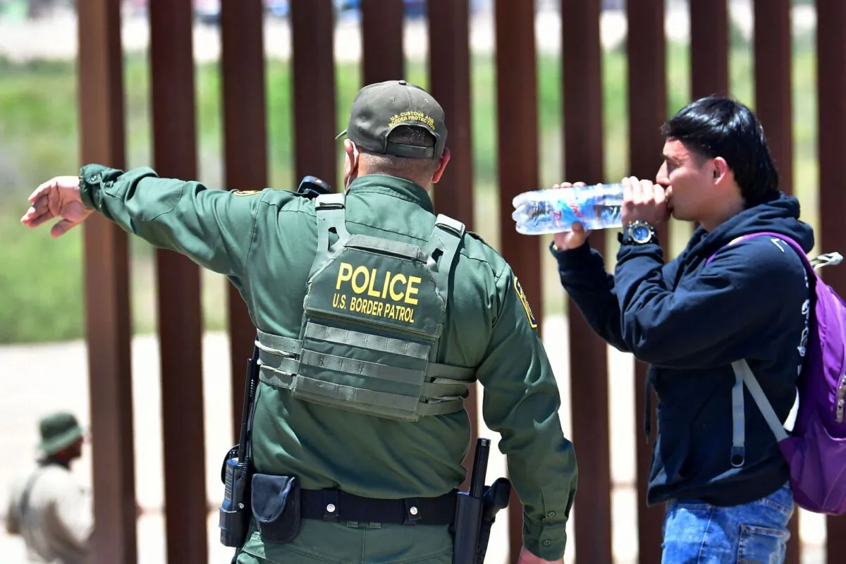 A U.S. Border Patrol agent directs an illegal alien after he crossed into the United States from Mexico through a gap in the border wall separating Algodones, Mexico, from Yuma, Arizona, on May 16, 2022. (Frederic J. Brown/AFP via Getty Images)