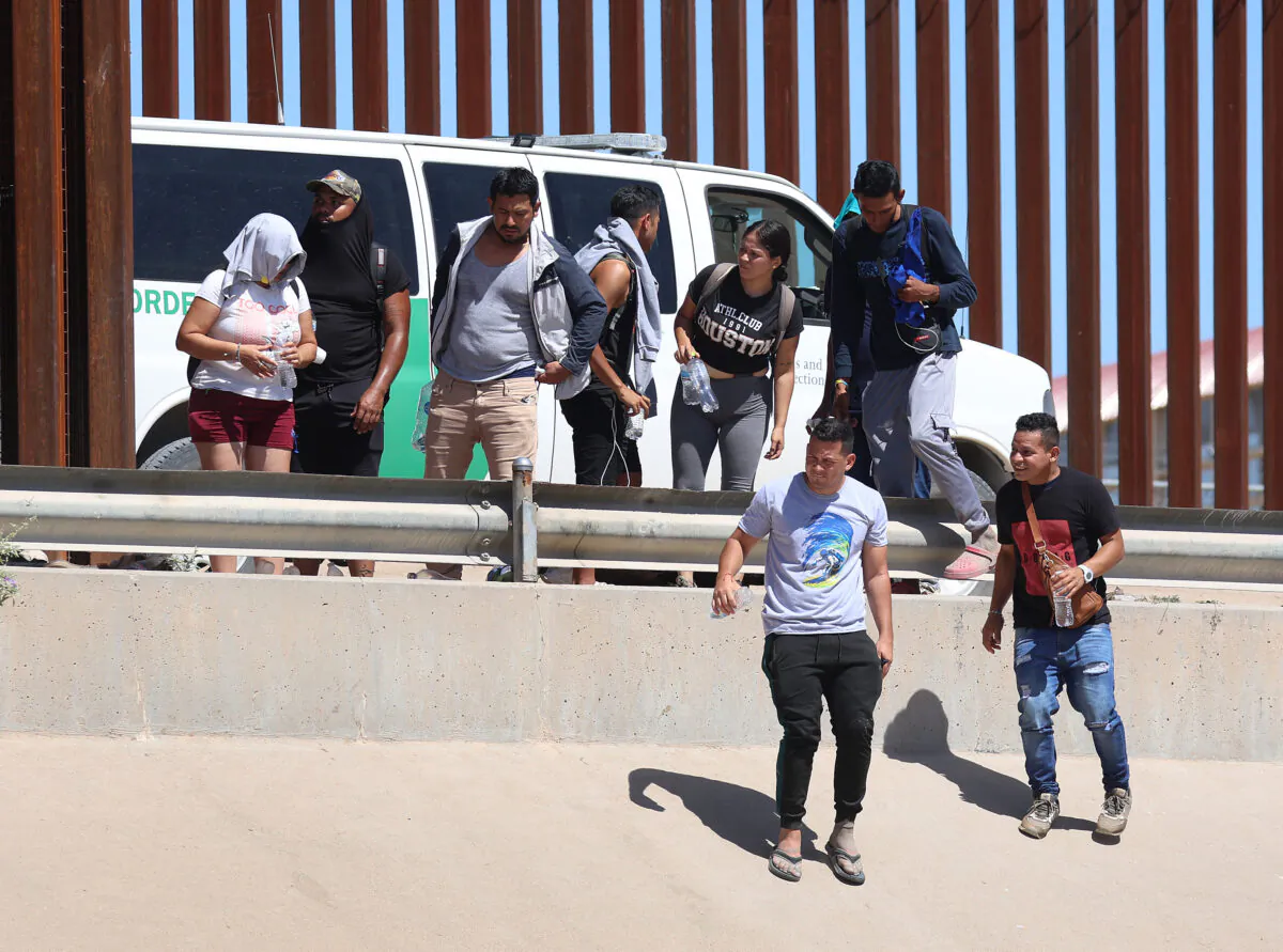 Venezuelan nationals walk along the border fence to a waiting Border Patrol van after illegally crossing the Rio Grande from Mexico, in El Paso, Texas, on Sept. 21, 2022. (Joe Raedle/Getty Images)