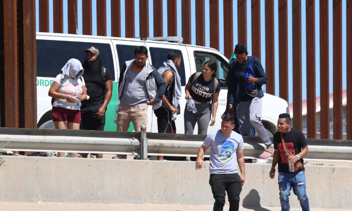 Venezuelan nationals walk along the border fence to a waiting Border Patrol van after illegally crossing the Rio Grande from Mexico, in El Paso, Texas, on Sept. 21, 2022. (Joe Raedle/Getty Images)