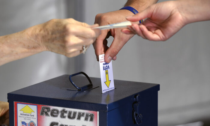 2022 年 10 月 22 日，在拉斯维加斯一家购物中心的帐篷内进行面对面提前投票的第一天，一名选民在投票后归还了一张选民卡。（大卫贝克尔/盖蒂图片社）