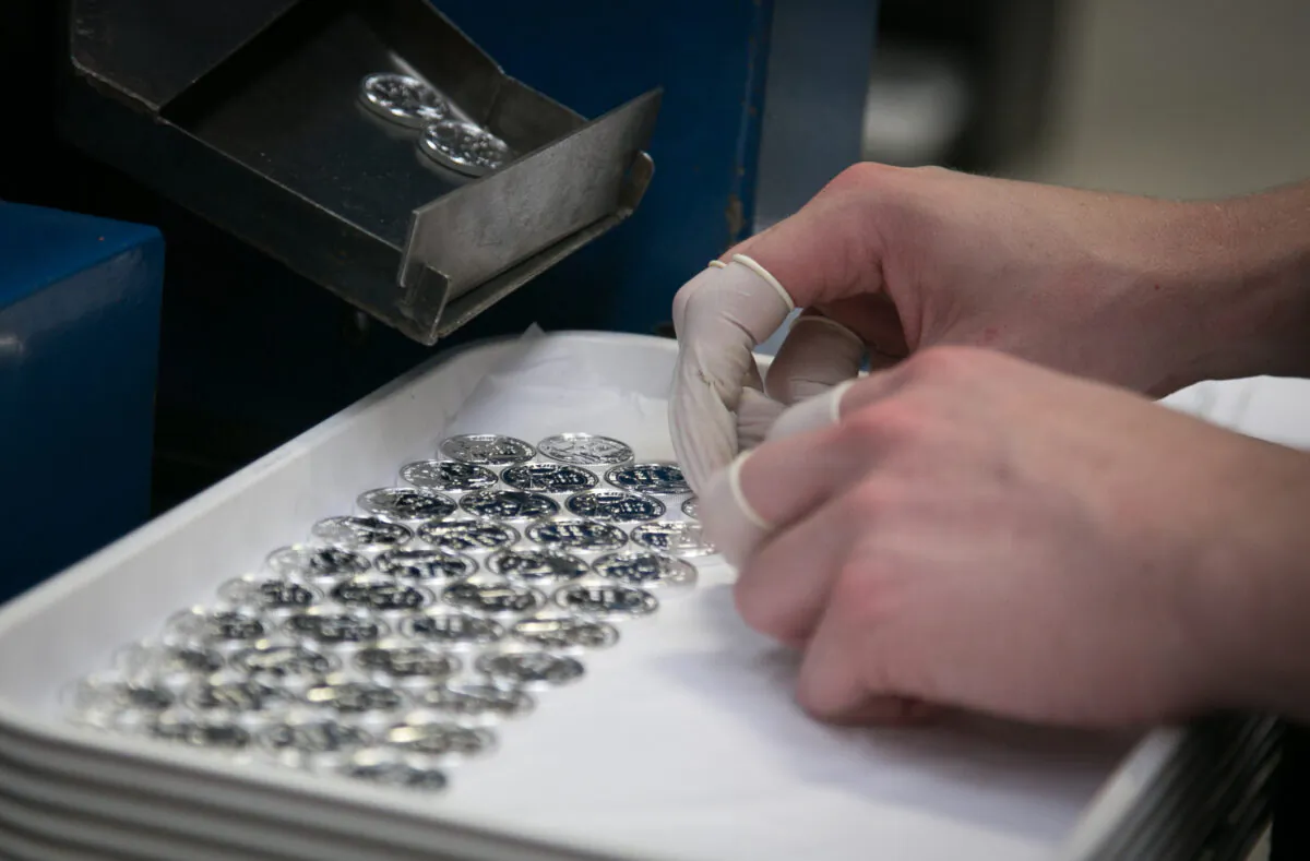 A member of staff inspects a new silver coin at the Royal Mint in Llantrisant, Wales, on Aug. 1, 2014. (Matt Cardy/Getty Images)